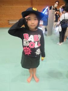 女の子が警察官の帽子を被って敬礼している状況