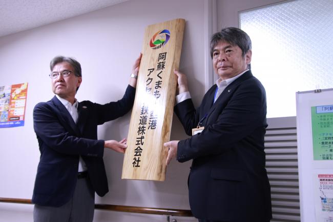 「阿蘇くまもと空港アクセス鉄道株式会社」の看板を設置する亀崎直隆代表取締役（右）、受島章太郎取締役（左）
